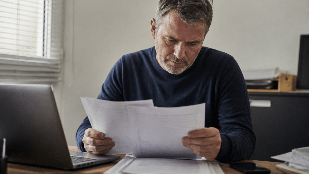 Homme consultant documents fiscaux à son bureau.