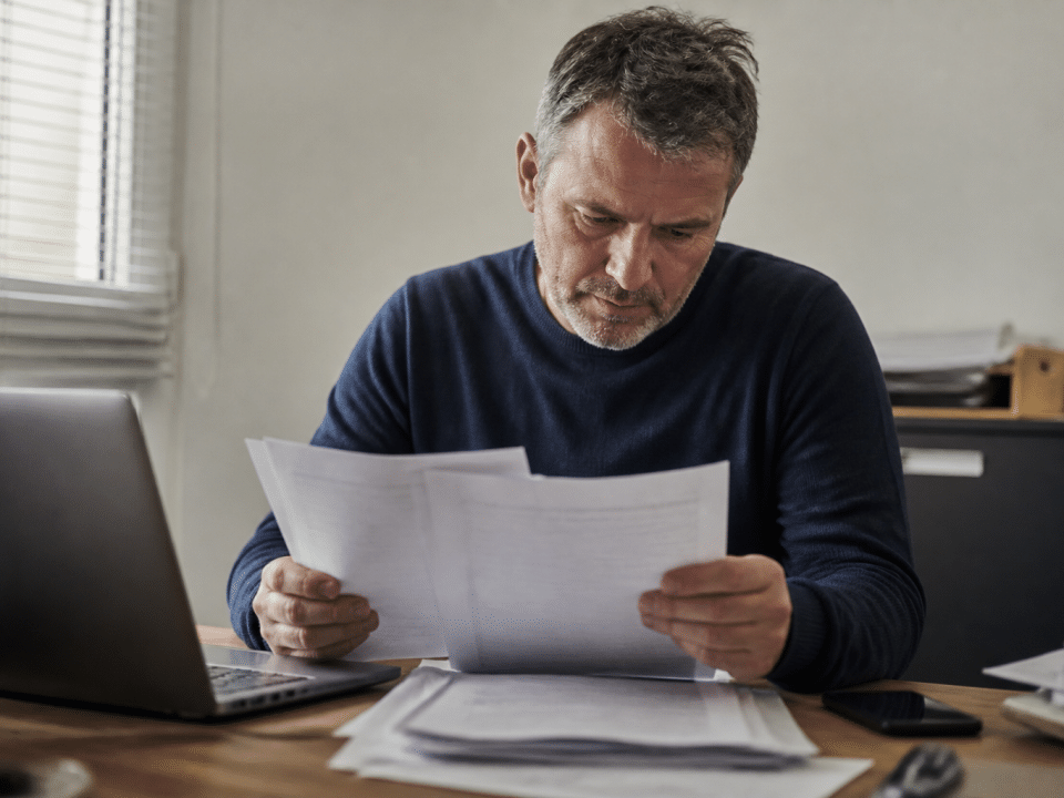 Homme consultant documents fiscaux à son bureau.