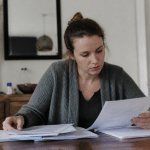 Femme assise consultant documents administratifs avec formulaire.