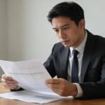 Homme consultant documents financiers à son bureau.