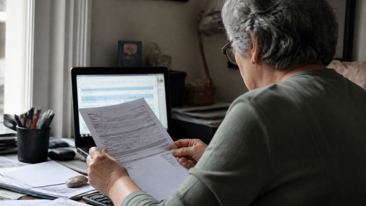 Personne assise devant ordinateur consultant documents financiers retraite.