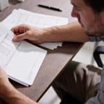 Personne examinant documents financiers a table bureau