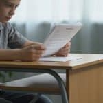 Adolescent consulte documents administratifs sur bureau