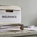 Classeur contenant documents assurances empiles sur bureau desordonne