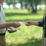 Un couple âgé échange des billets d'argent dans un parc.