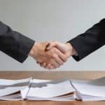 Deux personnes se serrent la main devant documents