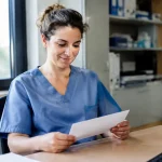 Agent hospitalier assis tenant une enveloppe sur un bureau