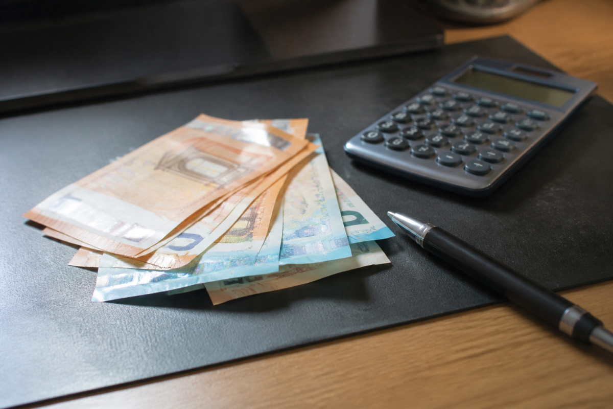 Billets en euros, calculatrice et stylo sur bureau