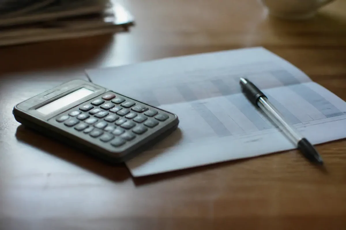 Calculatrice et stylo poses sur une feuille de paie