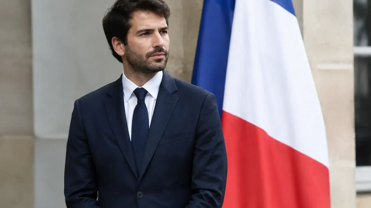 Homme en costume debout devant un drapeau tricolore