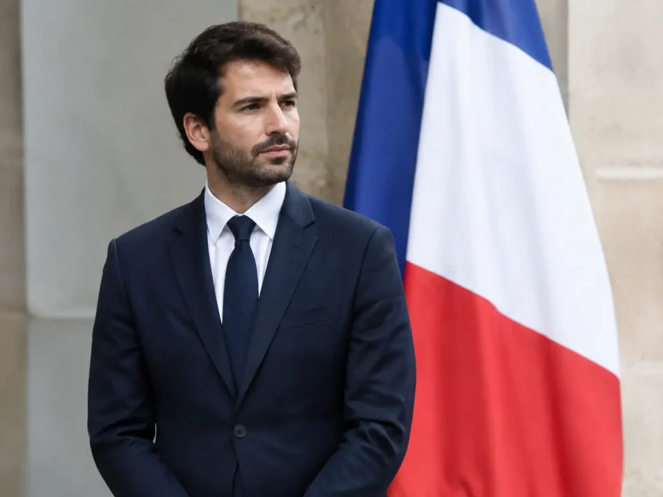 Homme en costume debout devant un drapeau tricolore