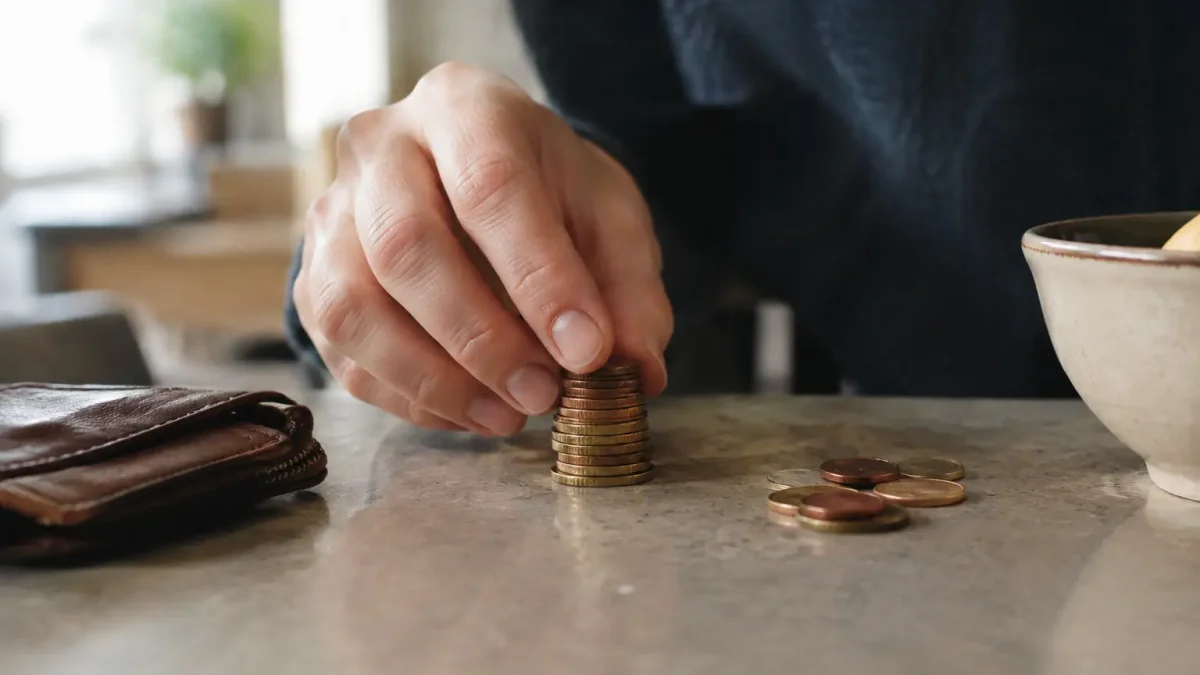 Main posant une pile de pieces sur un comptoir