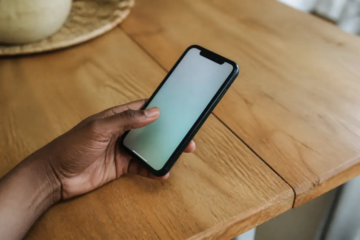 Main tenant smartphone affichant solde sur table en bois