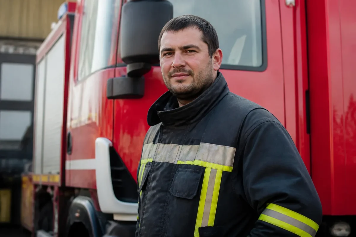 Sapeur-pompier en tenue devant un camion rouge