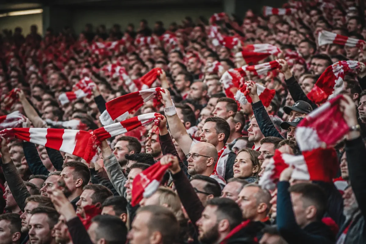 Tribunes bondees de supporters agitant des echarpes rouges